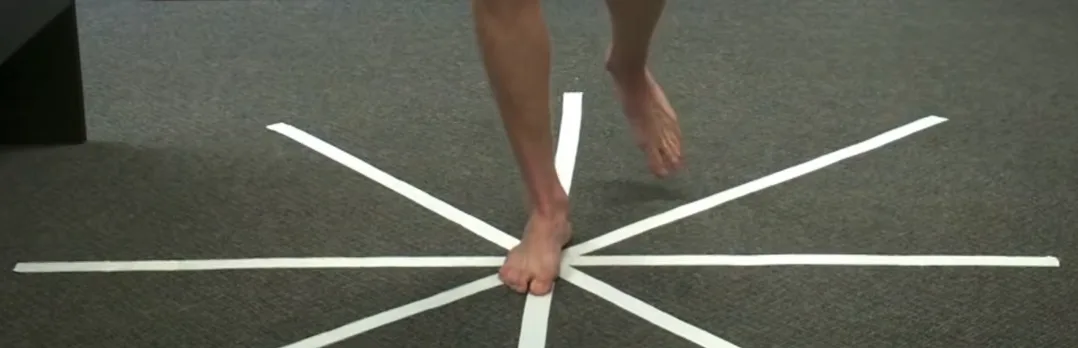 Star Excursion Balance Test grid taped on a carpet floor, with the stance foot on the centre point pointing toward the anterior line